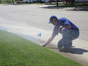 a Pittsburg CA Sprinkler Repair tech adjusts a pop up head